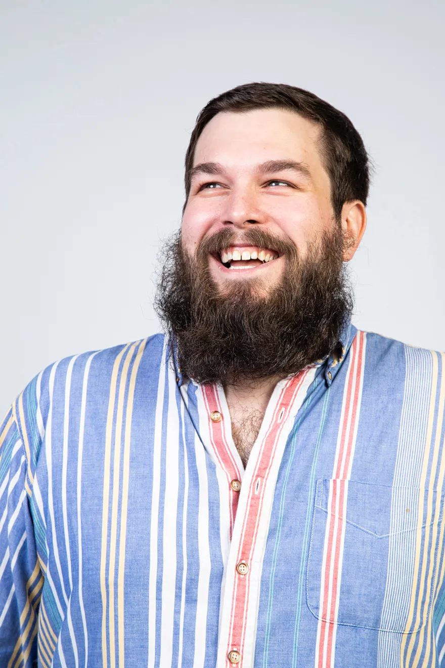 Jason Melton smiling in a striped shirt against a light background.